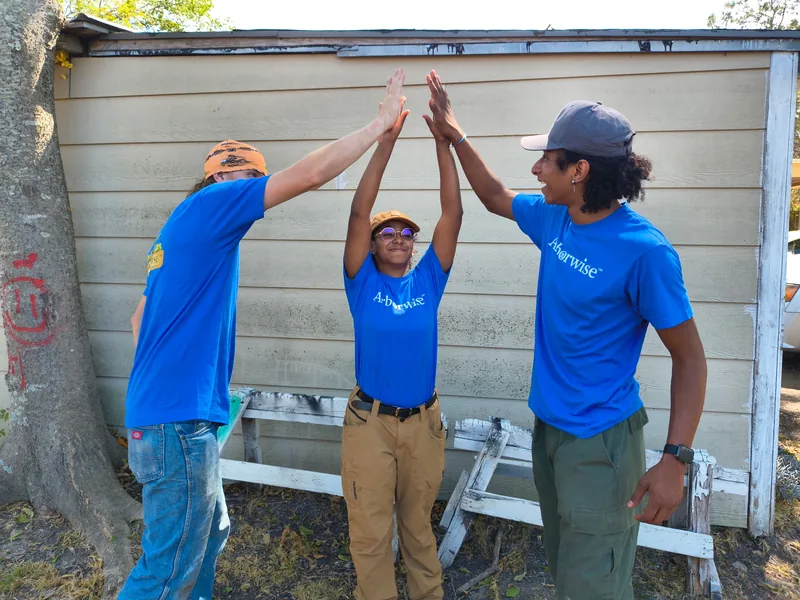 Three Arborwise crew members meeting in a three-way high five at the end of a training day in Bonham