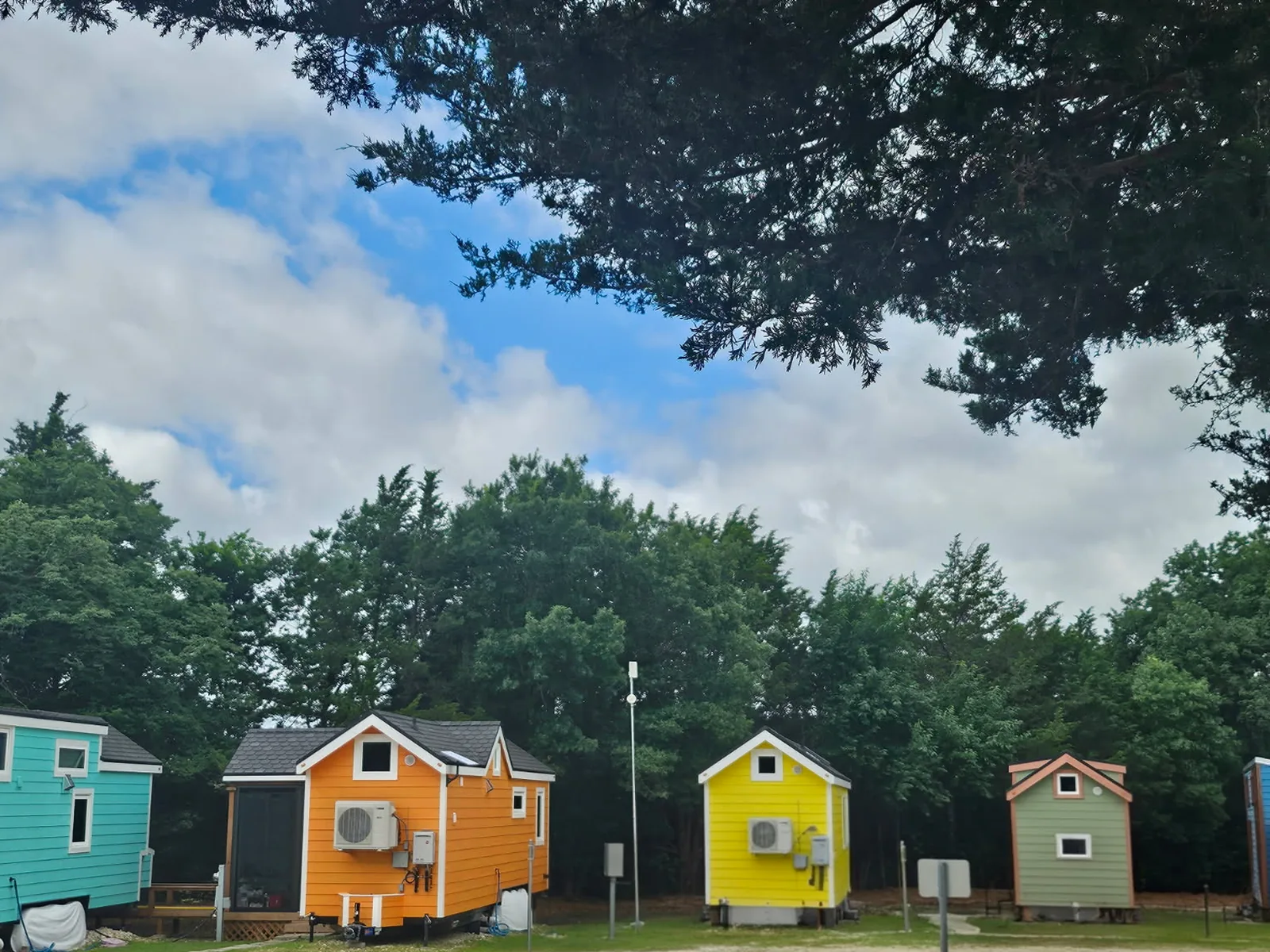 Brightly painted tiny homes under the trees at NamaStay Hideaway, a tiny living community outside Van Alstyne